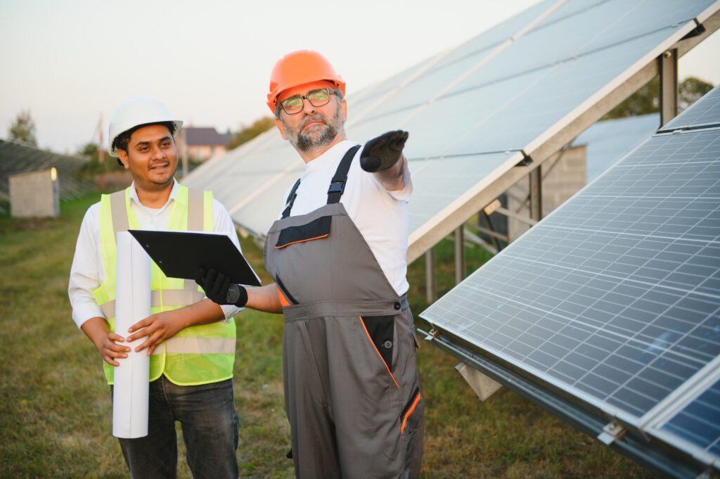 Zwei Männer mit Laptop vor Solaranlage, die den Praxis-Guide für Hausbesitzer besprechen