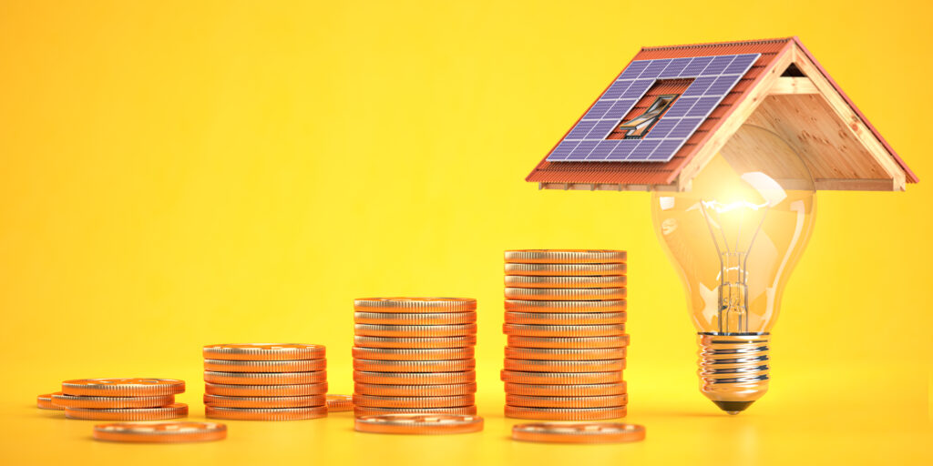Münzentürme und ein Solardach auf einer Glühbirne als Zeichen für Geld bei Solar sparen
